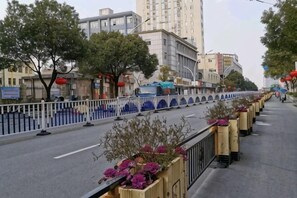 A street with a white fence, trees, and buildings.