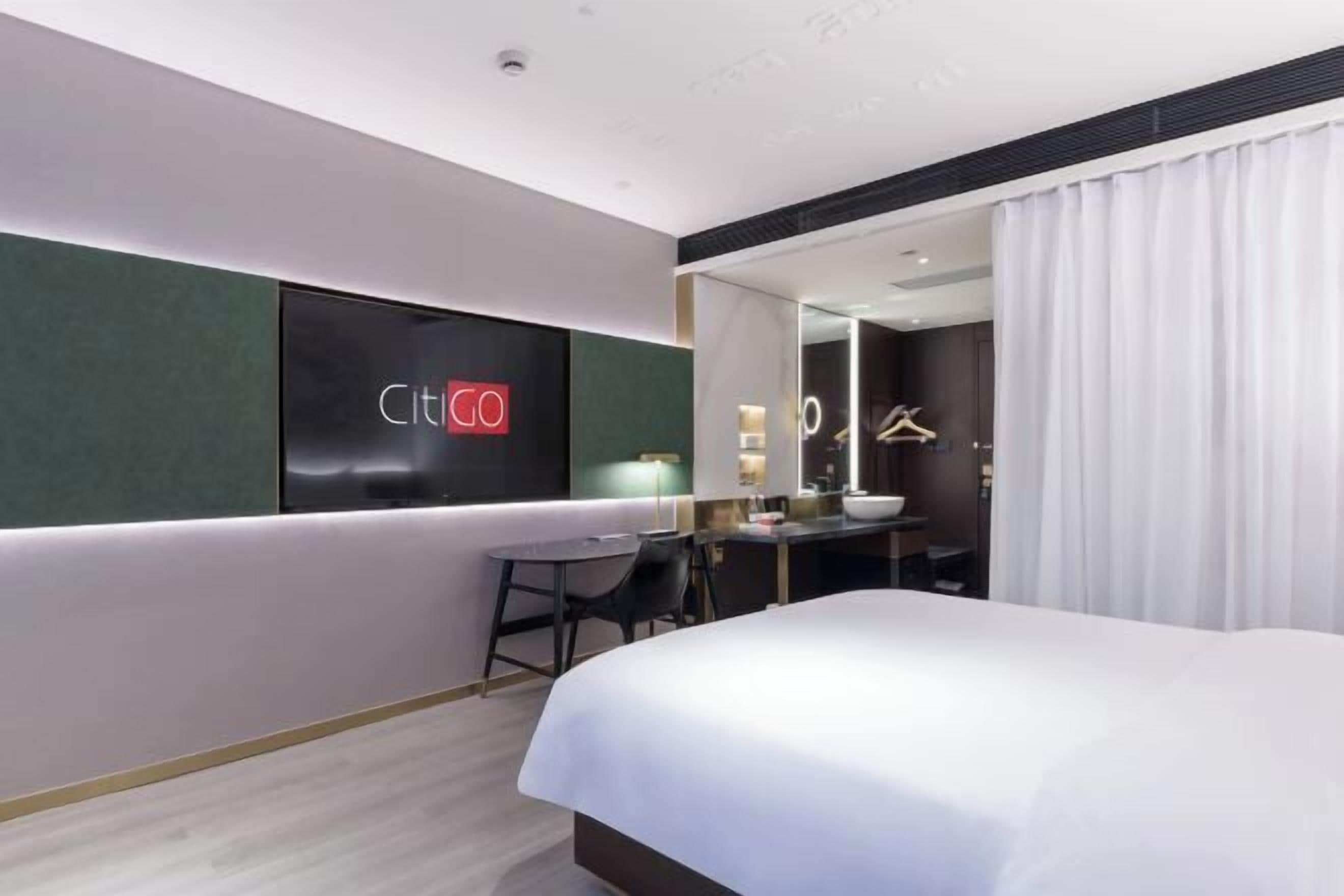 Habitació d'hotel moderna amb un llit gran, una taula de treball i un mirall.