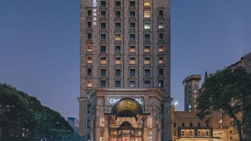 A tall hotel with a classic facade, multiple floors, and a prominent entrance with an arched roof.