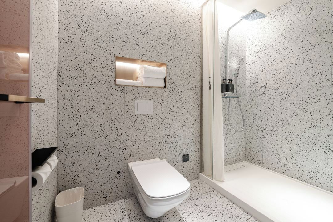 Une salle de bain moderne avec des toilettes sur pied, une douche à parois de verre et un porte-serviettes.