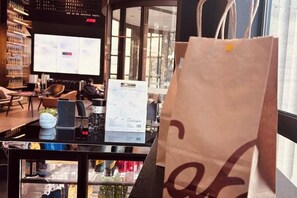 A coffee shop interior with a table, chairs, and a large paper bag. - CitiGO Hotel, Jinqiao, Shanghai (Shanghai)