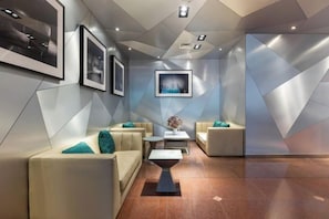 A modern lobby with a geometric wall design, seating area with couches and a coffee table, and framed artwork on the walls. - Tongnan Hotel (Chongqing)