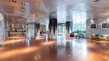 A spacious lobby with a polished floor, seating areas, and a large window providing natural light.