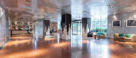A spacious lobby with a polished floor, seating areas, and a large window providing natural light.