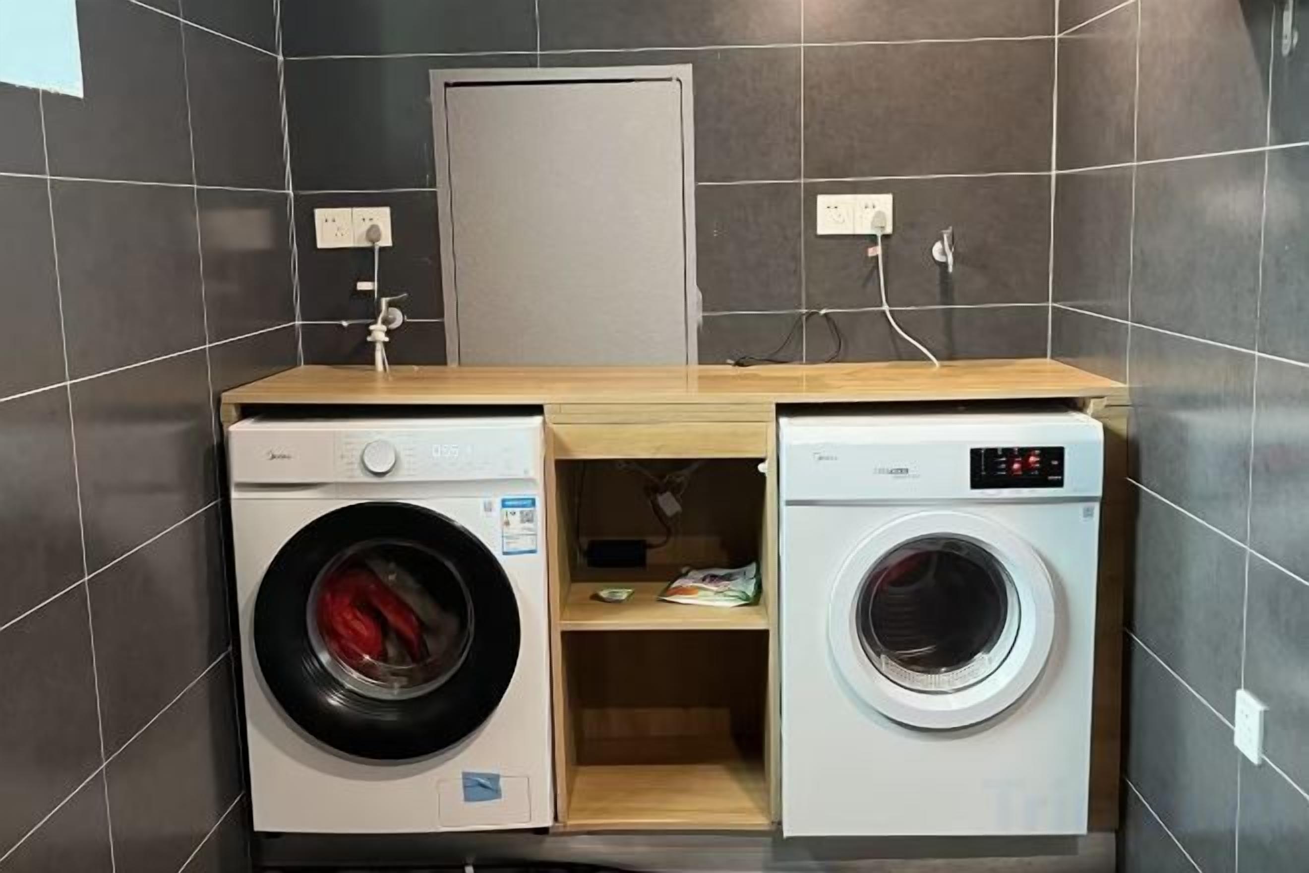 Een kleine wasruimte met twee wasmachines, een houten aanrechtblad en een deur op de achtergrond.