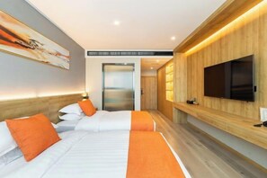 Ein modernes Hotelzimmer mit zwei Betten, einem großen Fernseher und einer Wand mit Holzvertäfelung.