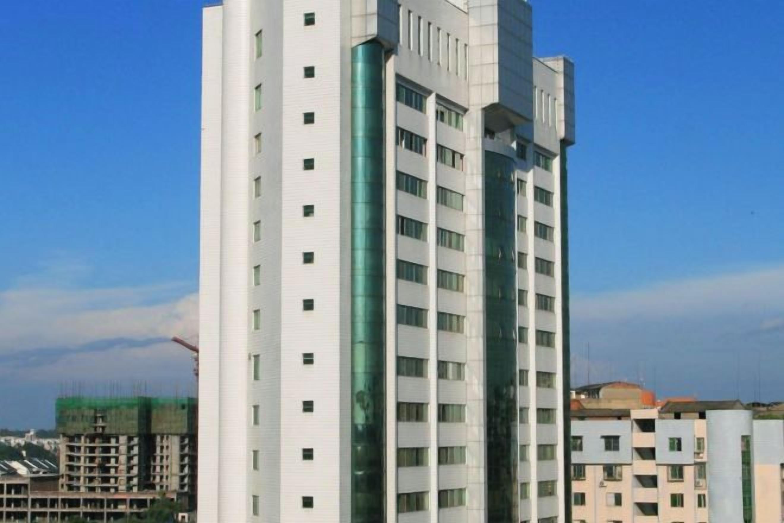 A multi-story building with a modern architectural design, featuring a central glass facade and a series of balconies.