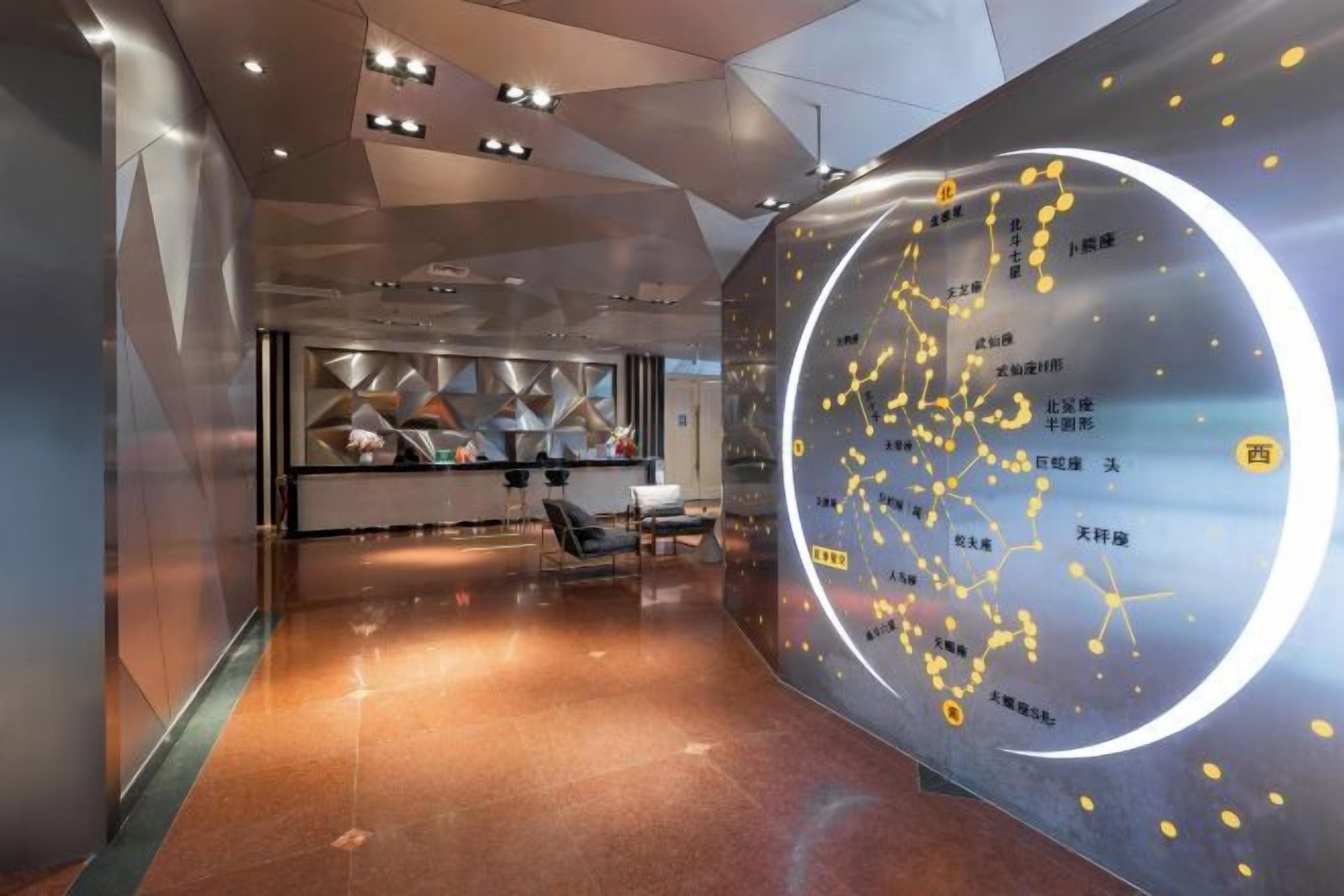 Eine moderne Lobby mit einer runden Wandgestaltung, die Text und Symbole zeigt, einem Empfangsbereich und einer Sitzgelegenheit.