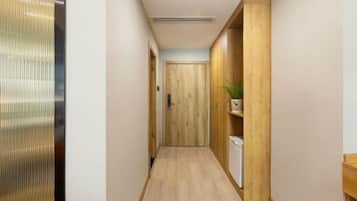 Un couloir étroit aux murs en bois, avec une porte en bois au bout.