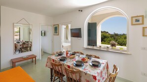 A dining area with a table set for six, a mirror, and a TV on the wall. - 4038 Bliss Attico Fronte Mare by Barbarhouse (Porto Cesareo)
