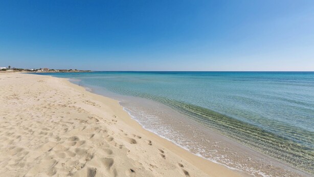 A wide sandy beach with clear blue water and a few footprints. - 4038 Bliss Attico Fronte Mare by Barbarhouse (Porto Cesareo)