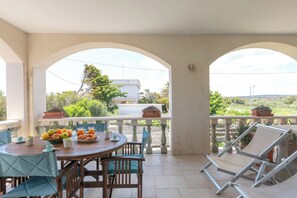 Uma área de refeições ao ar livre coberta, com uma mesa posta para o pequeno-almoço, rodeada por cadeiras e com vista para uma paisagem deslumbrante.
