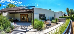 Une maison moderne dotée d’un patio couvert, d’un espace salon extérieur et d’une variété de plantes.