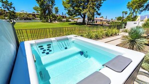 A hot tub with a control panel, surrounded by a landscaped garden and a clear view of the surrounding area.
