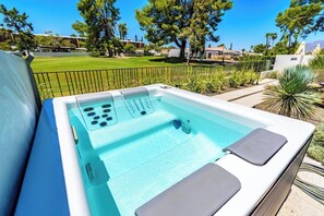 A hot tub with a control panel, surrounded by a landscaped garden and a clear view of the surrounding area.