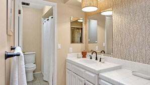 A bathroom with a toilet, sink, and mirror.