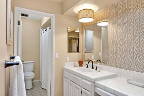 A bathroom with a toilet, sink, and mirror.
