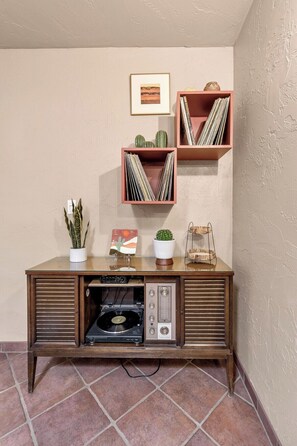 A vintage radio cabinet with a turntable, surrounded by decorative items and a framed picture on the wall. - Dorado Golf Villa,Pet Friendly (Tucson)