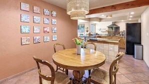 A dining area with a round wooden table, chairs, and a hanging light fixture.