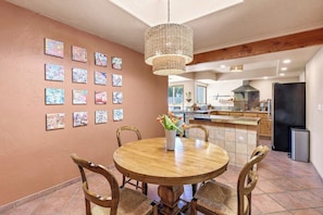A dining area with a round wooden table, chairs, and a hanging light fixture.
