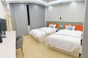 A hotel room with two beds, a desk, a chair, and a TV.