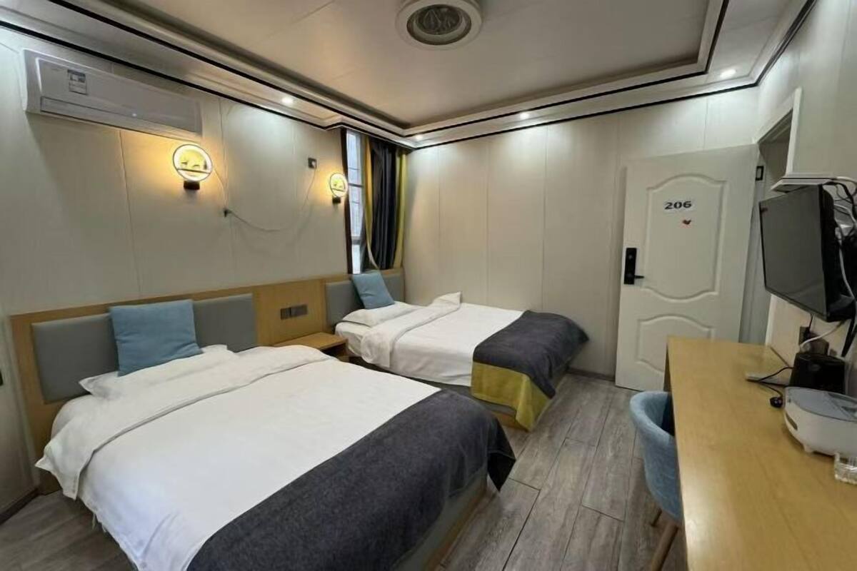 A hotel room with two beds, a desk, a television, and a door labeled '206'.