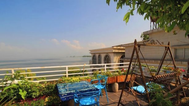 An outdoor patio with a table and chairs, surrounded by potted plants and a swing chair. - Chenfan Lake View Inn (Dali City)