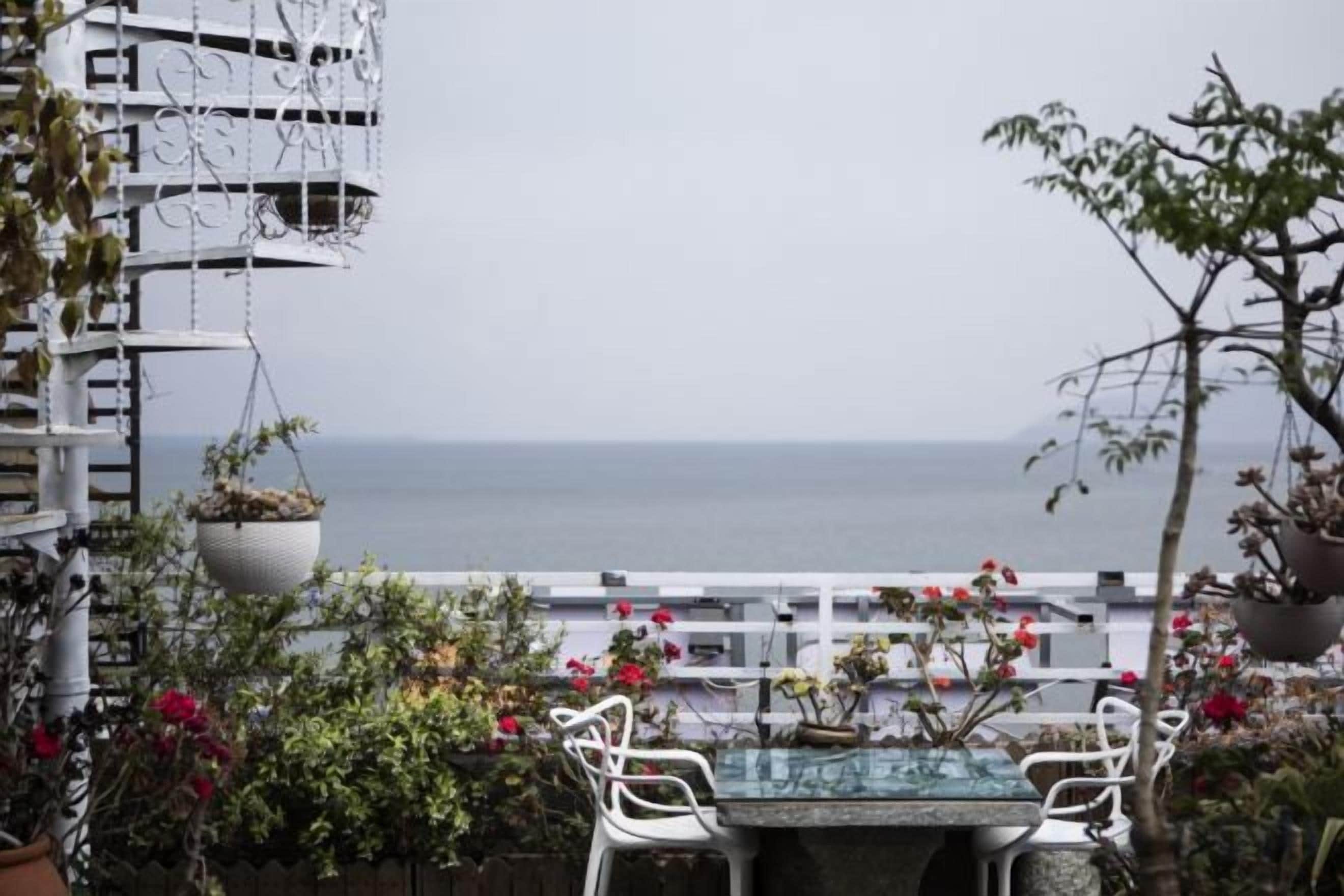 A terrace with a table and chairs, overlooking the sea.