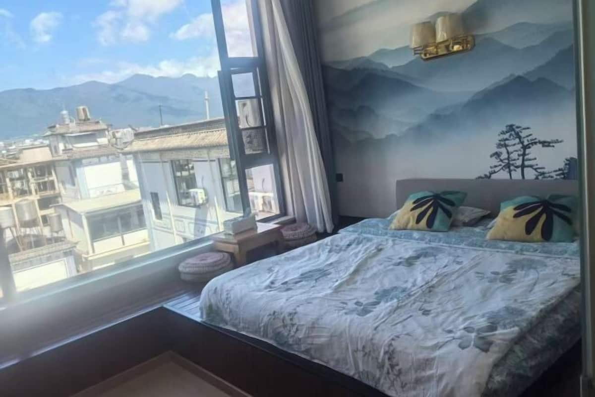 A bedroom with a bed, pillows, a window, and a wall mural.