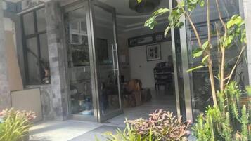 A modern interior with a glass door entrance, a dining area with a table and chairs, and indoor plants.