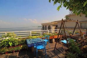 A terrace with a table and chairs, a swing, and a view of the sea.