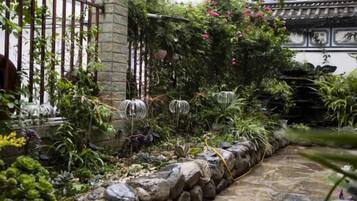 Un jardín con un sendero de piedra, una cerca de metal y diversas plantas.