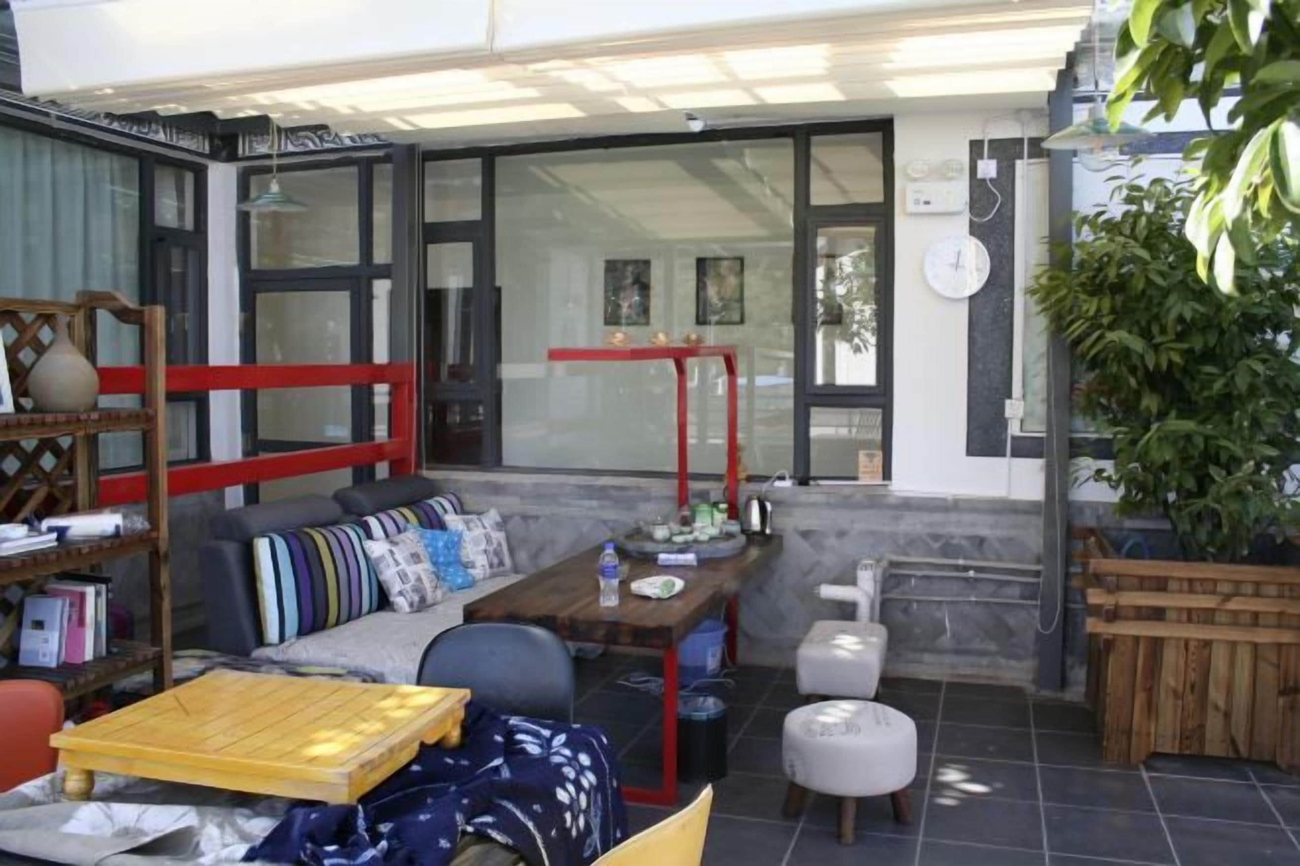 A modern living area with a sofa, dining table, and chairs, a bookshelf, and a red metal structure.
