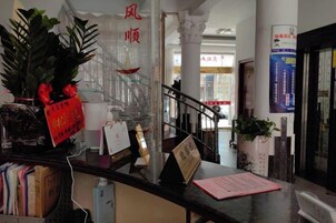 Una recepción con una planta en maceta, un letrero rojo y una escalera al fondo.