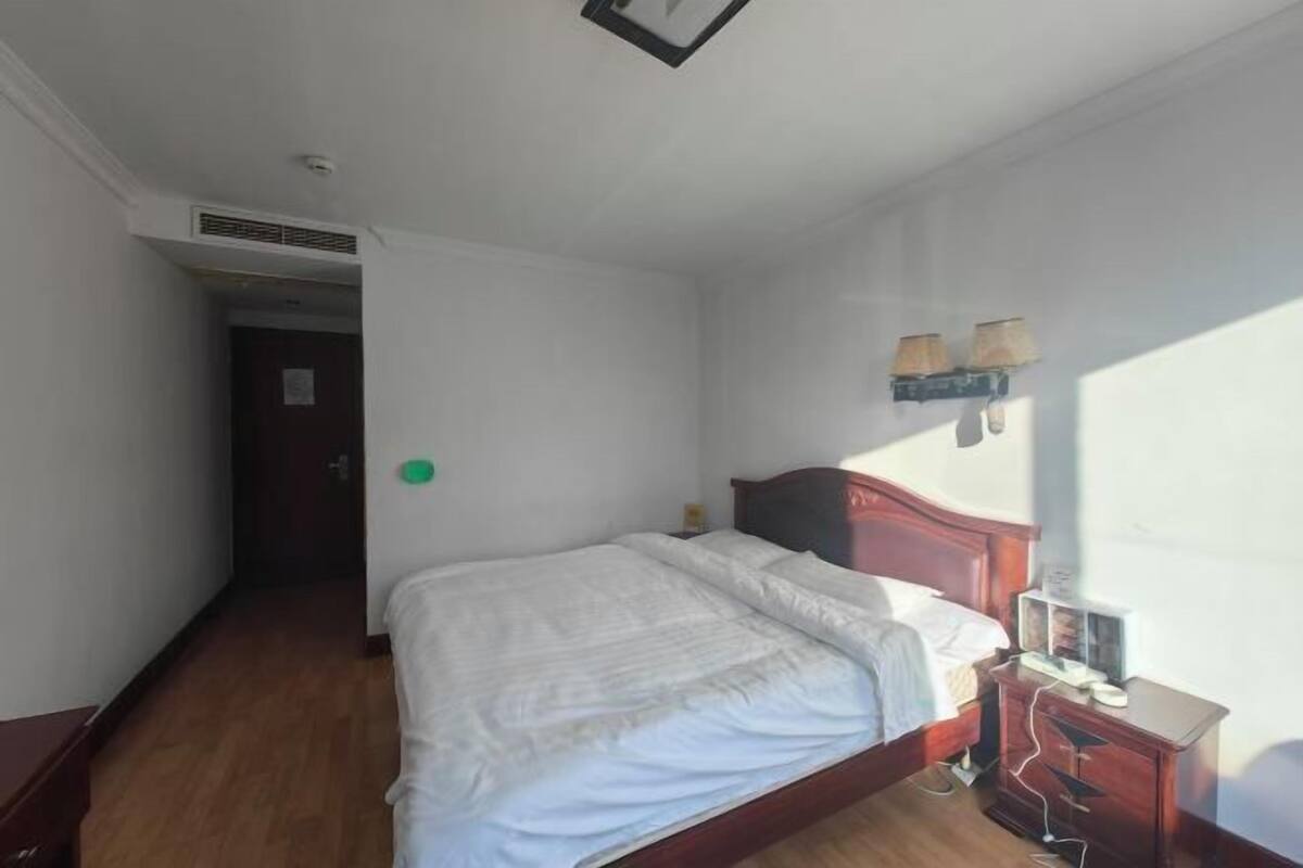 Ein Schlafzimmer mit einem hölzernen Bett, einem Nachttisch, einer Lampe und einer Wandleuchte.
