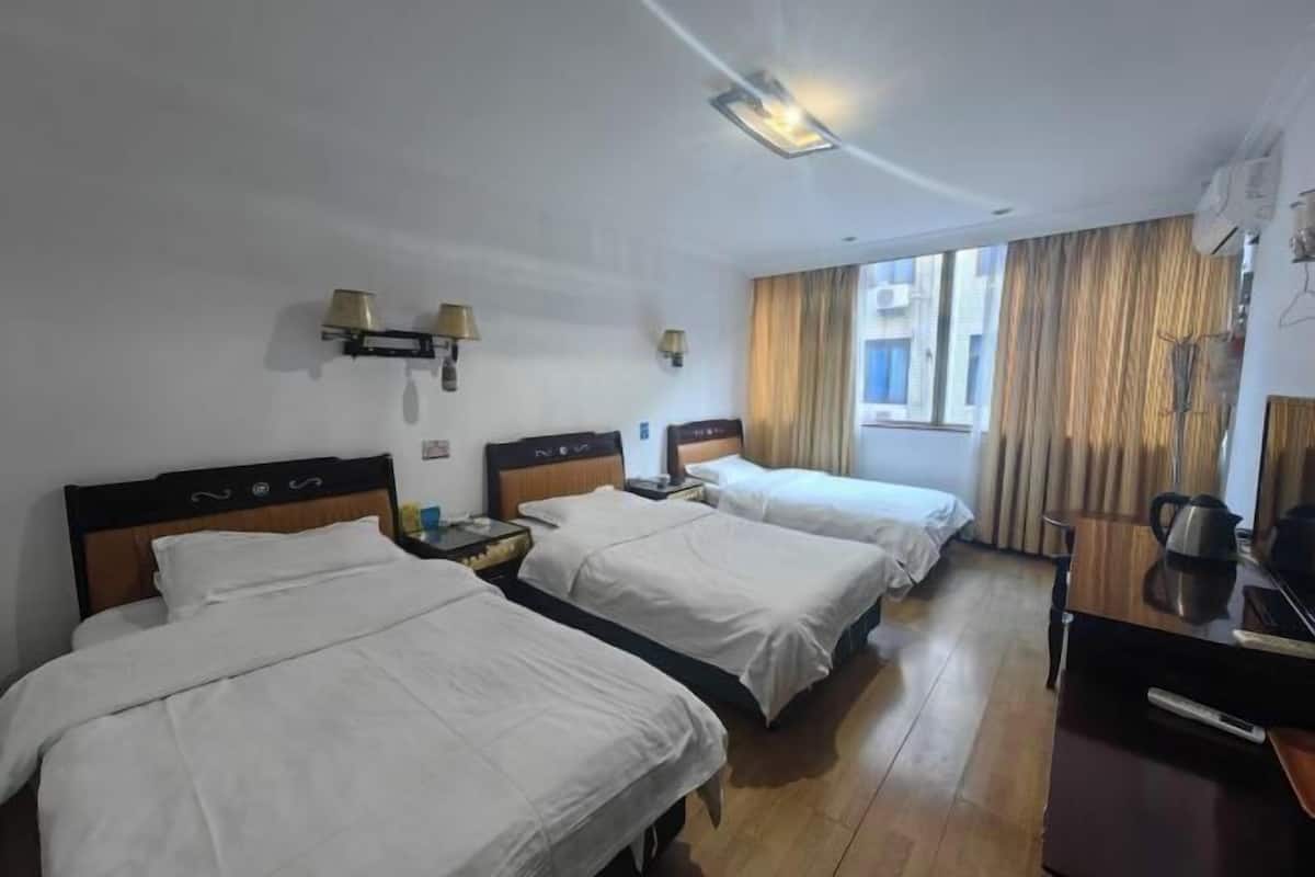 Ein Hotelzimmer mit zwei Betten, einem Schreibtisch, einem Stuhl, einer Lampe und einem Fenster mit Vorhängen.