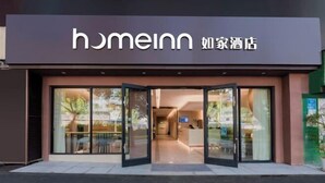 A hotel entrance with a glass door, a reception desk, and a sign with the hotel name.