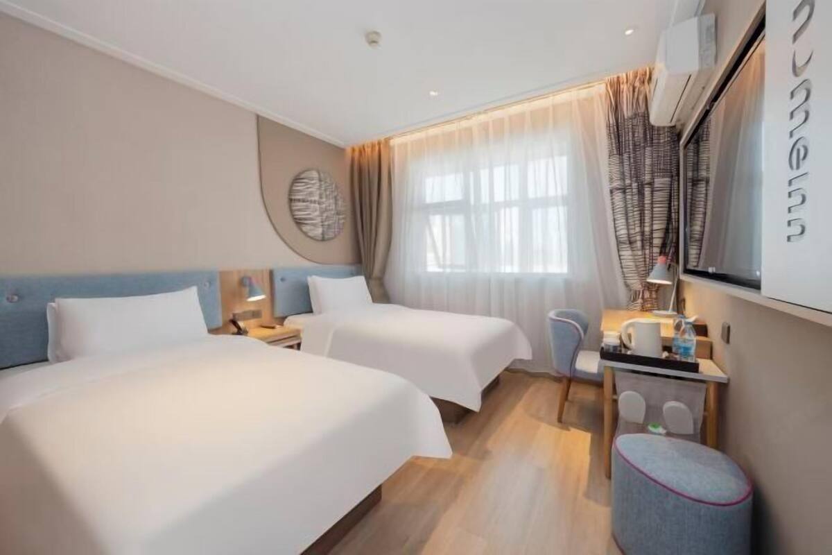 A hotel room with two beds, a desk, and a chair.