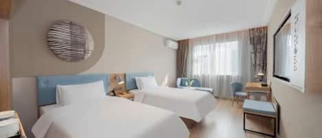 A hotel room with two beds, a desk, a chair, and a small table.
