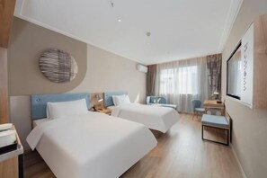 Een hotelkamer met twee bedden, een bureau, een stoel en een tafeltje.