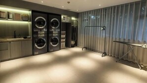 A modern laundry room with two washing machines, a drying rack, and a small table.