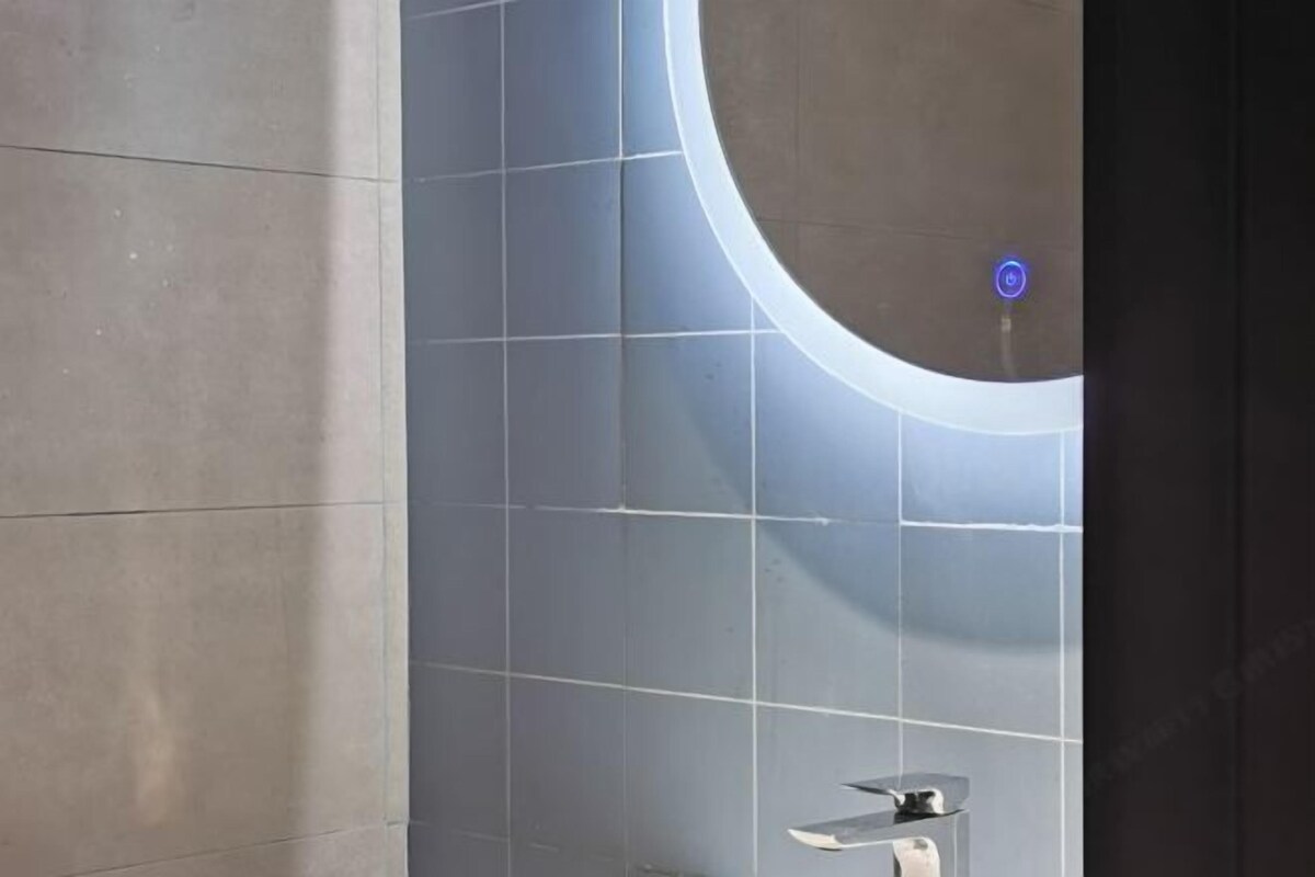 Een badkamer met een modern design, met een grote spiegel, een wandwastafel en een toilet.
