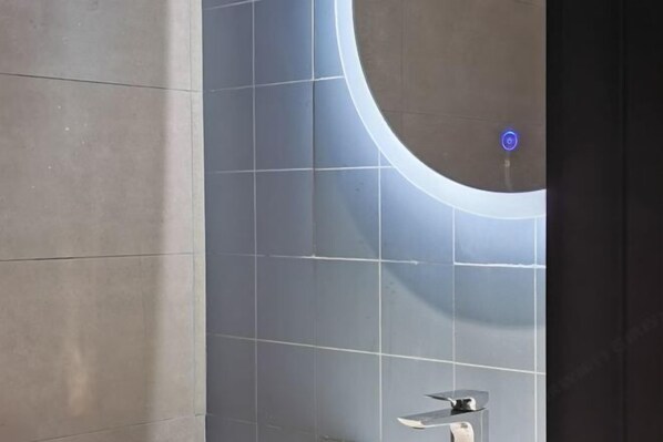 Een badkamer met een modern design, met een grote spiegel, een wandwastafel en een toilet.