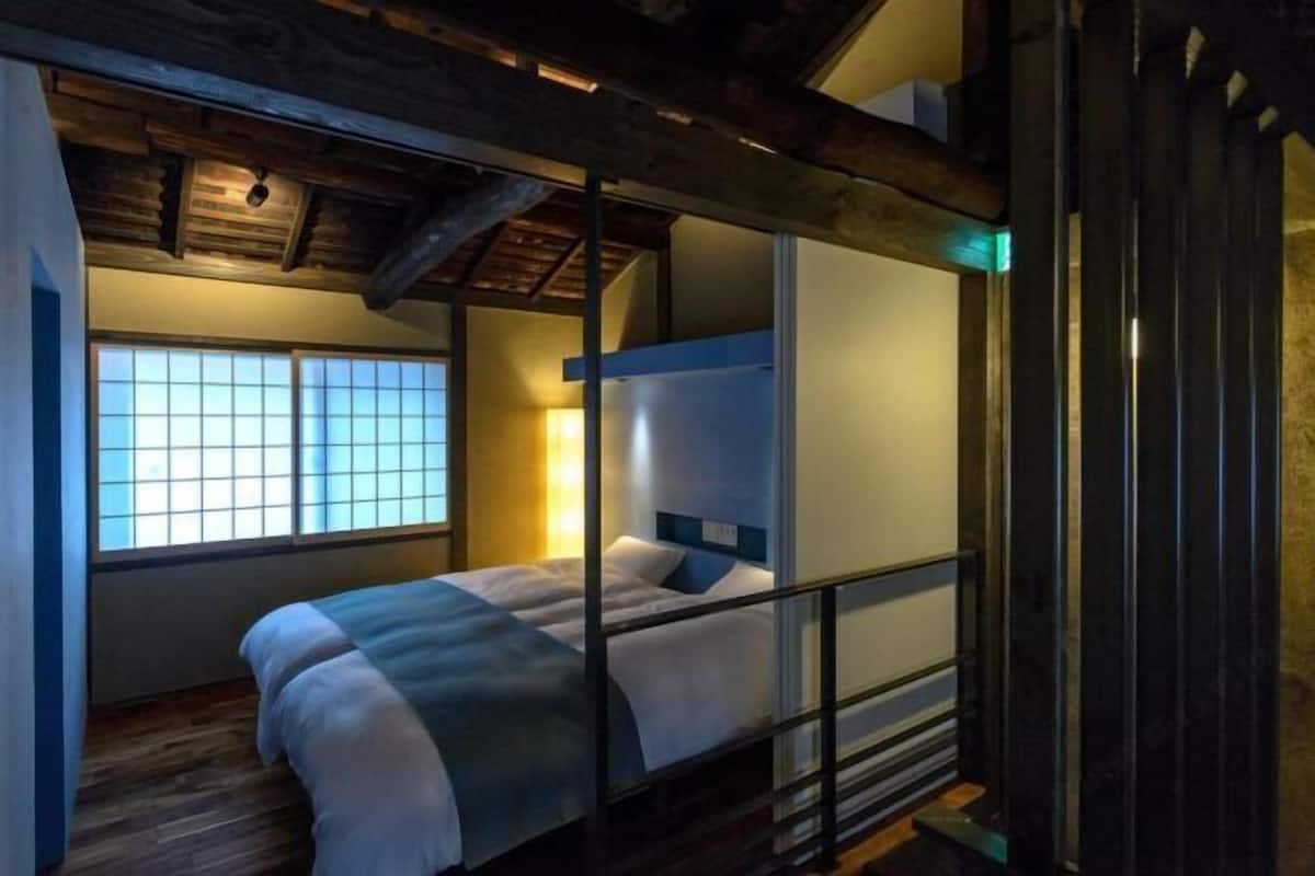 A room with a bed, a window with a view, and a wooden ceiling.
