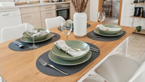 A dining table set with green plates, white napkins, and silverware. - Comfortable apartment near Basel with parking space (Weil am Rhein)