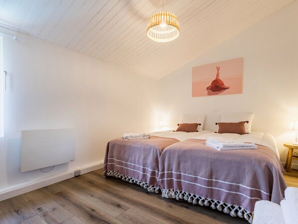 A bedroom with two beds, a wooden floor, a white radiator, and a hanging light fixture. - House with heated private pool, near beach in Pornic (Pornic)