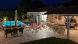 Ein Steinhhaus mit Swimmingpool, Sitzgelegenheiten im Freien und einer überdachten Terrasse.