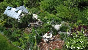 Un jardín con un pabellón, una escalera espiral metálica y un invernadero.