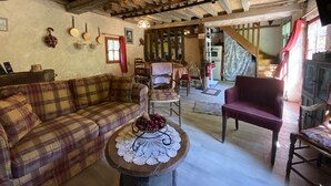 Una sala de estar rústica con un sofá a cuadros, una mesa de centro de madera con un mantel de encaje y un sillón rojo.