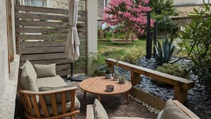 An outdoor seating area with a wooden table, two cushioned chairs, and a bench. - Apartment with terrace, garden and WIFI in the historic heart of Angoulême (Angoulême)